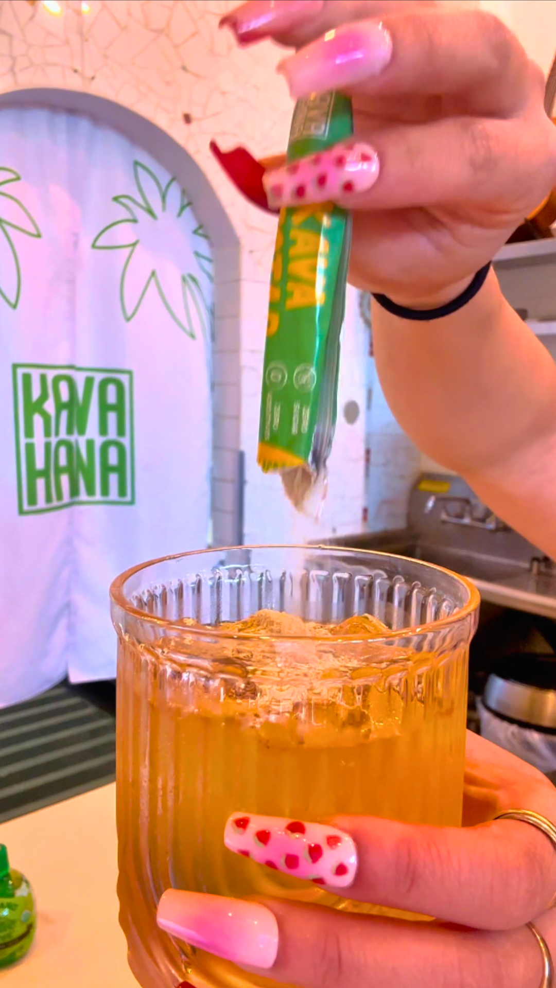 Pouring a Kava Nectar stick pack into a ribbed glass of iced apple juice to make an autumn spice kava drink. 