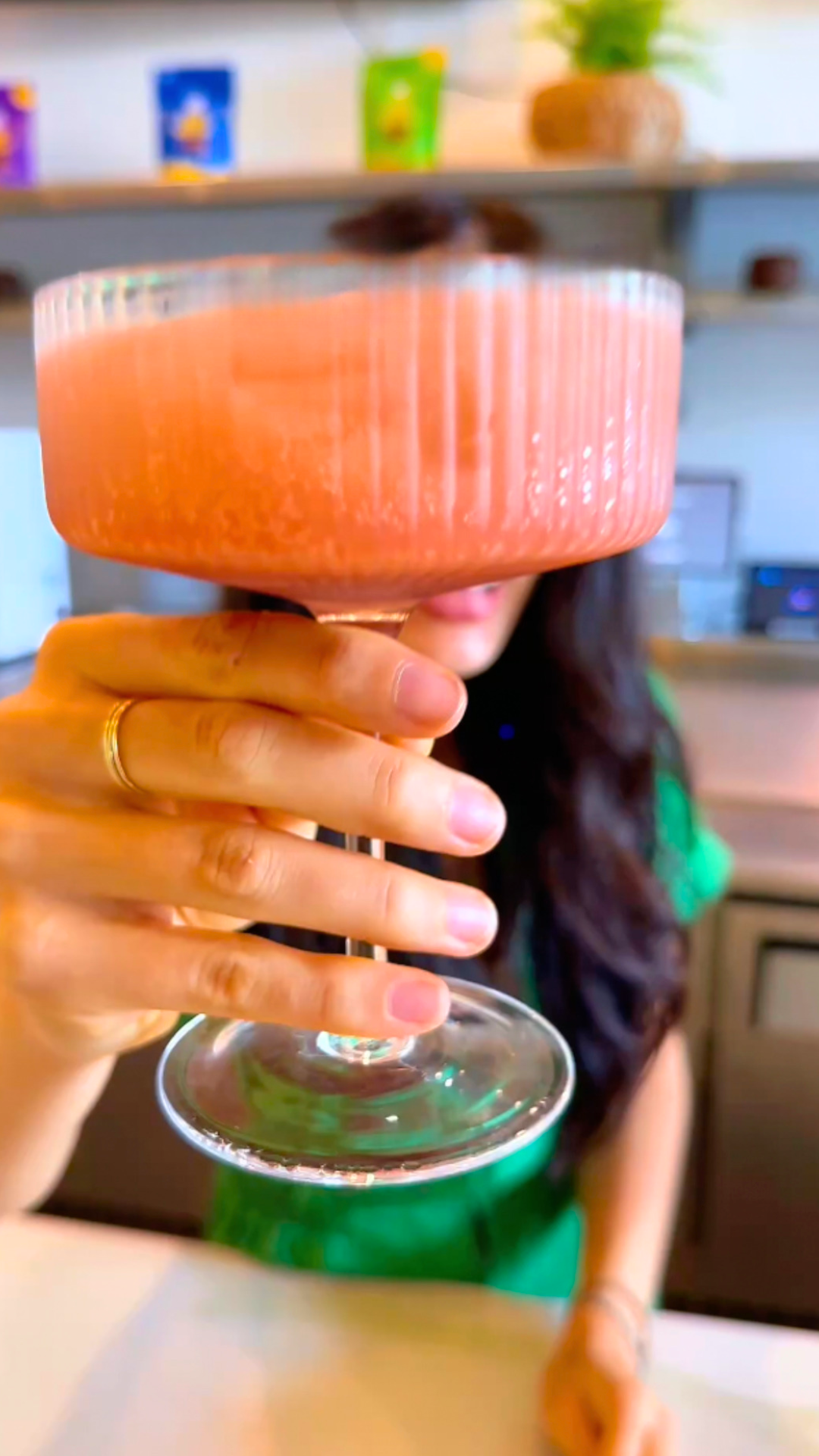 Holding up a pink Dirty Shirley Kava Nectar Mocktail in a ribbed coupe glass at the Kavahana bar