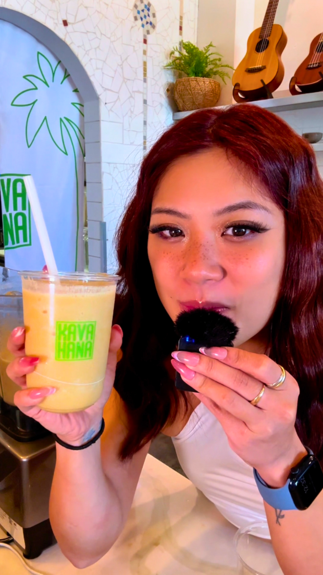 Holding a blended Pineapple Peach Kava Nectar drink in a Kavahana cup with a straw