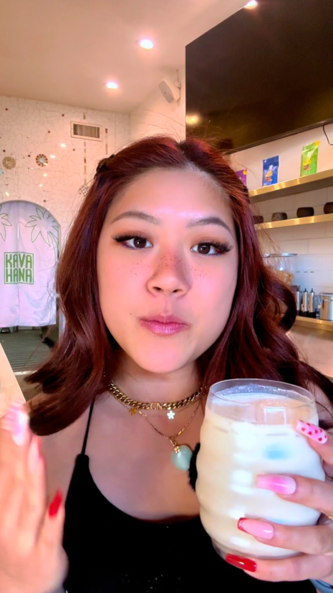 Holding a creamy Sugar Cookie Kava Nectar Mocktail over ice in a stemless glass at the Kavahana bar. 