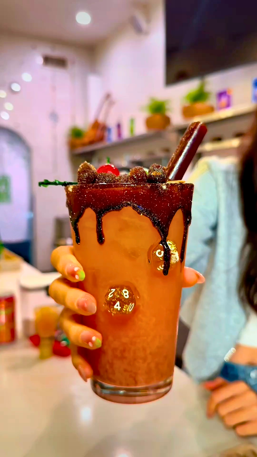 A tall Yuzu Mai Tai Kava Nectar Mocktail over ice with a chamoy-dripped, chili-sugar rim, topped with candied fruit, a cherry, and a tamarind straw.